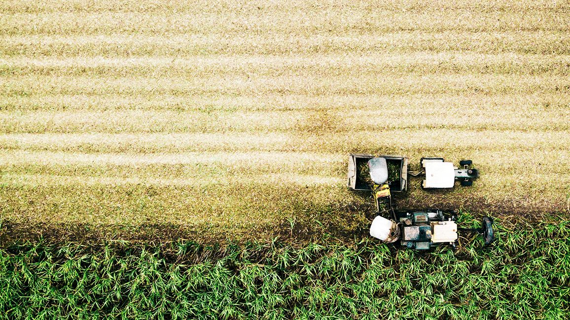 A robot car rests on a grassy field, with sensors and cables visible beside it.