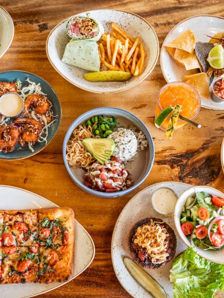 A colorful spread of assorted bowls and plates with noodles, rice, vegetables, and meats, artfully arranged for a vibrant meal.