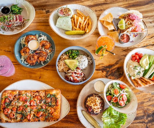A colorful spread of assorted bowls and plates with noodles, rice, vegetables, and meats, artfully arranged for a vibrant meal.