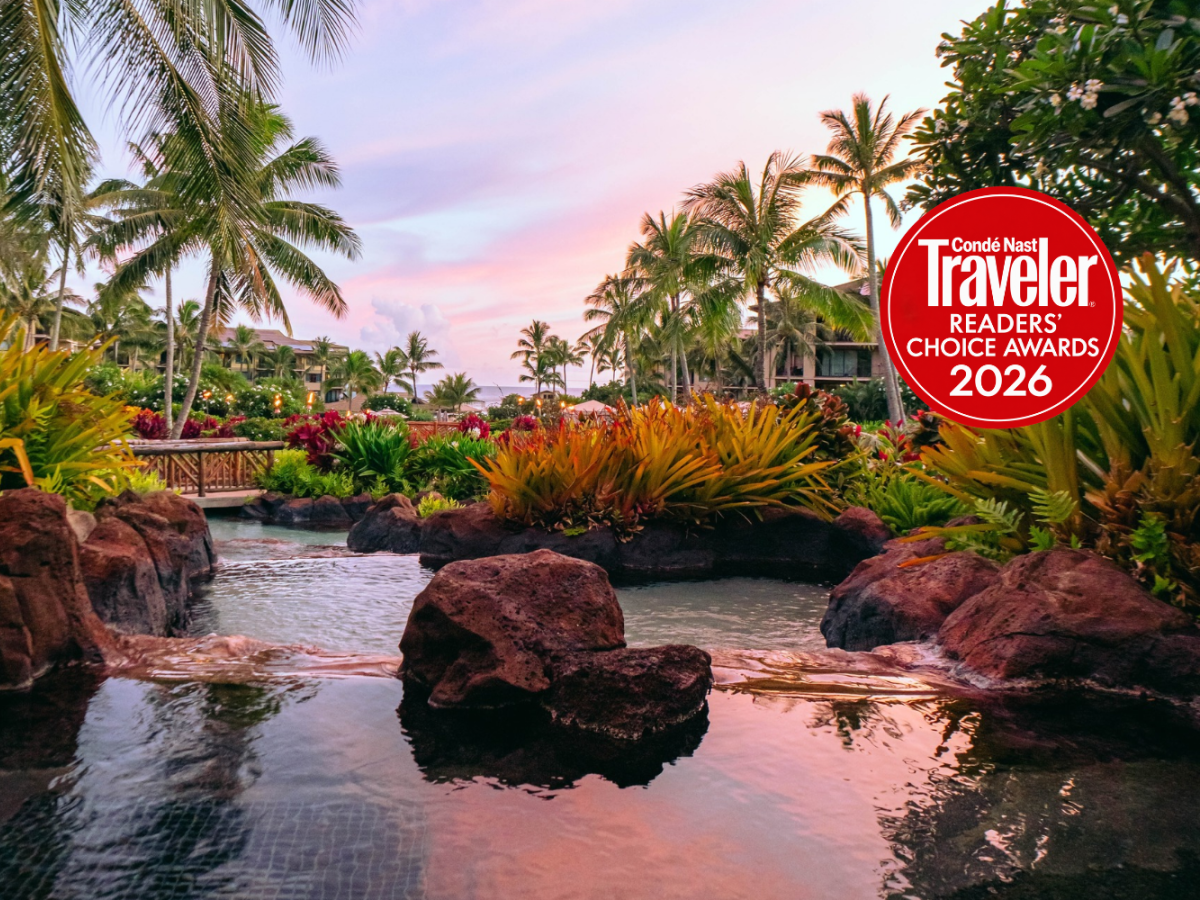 Tropical resort scene with palms, flowers, a small reflecting pool, and a &ldquo;Cond&eacute; Nast Traveler Readers&rsquo; Choice Awards 2026&rdquo; badge.