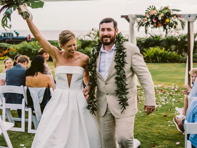 A bride throws her bouquet while her bearded groom, wearing a green garland, walks down a grassy outdoor wedding aisle.