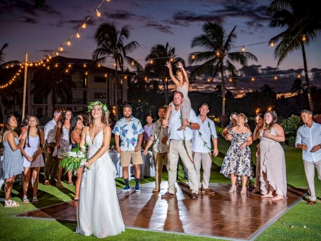 Bride and groom toast on a lit tropical lawn at a wedding, surrounded by friends and palm trees under string lights!