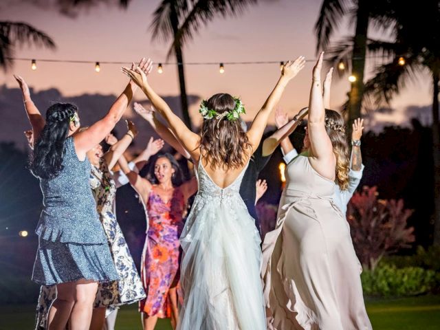 Bridesmaids and guests dance joyfully at an outdoor celebration under palm trees and string lights.